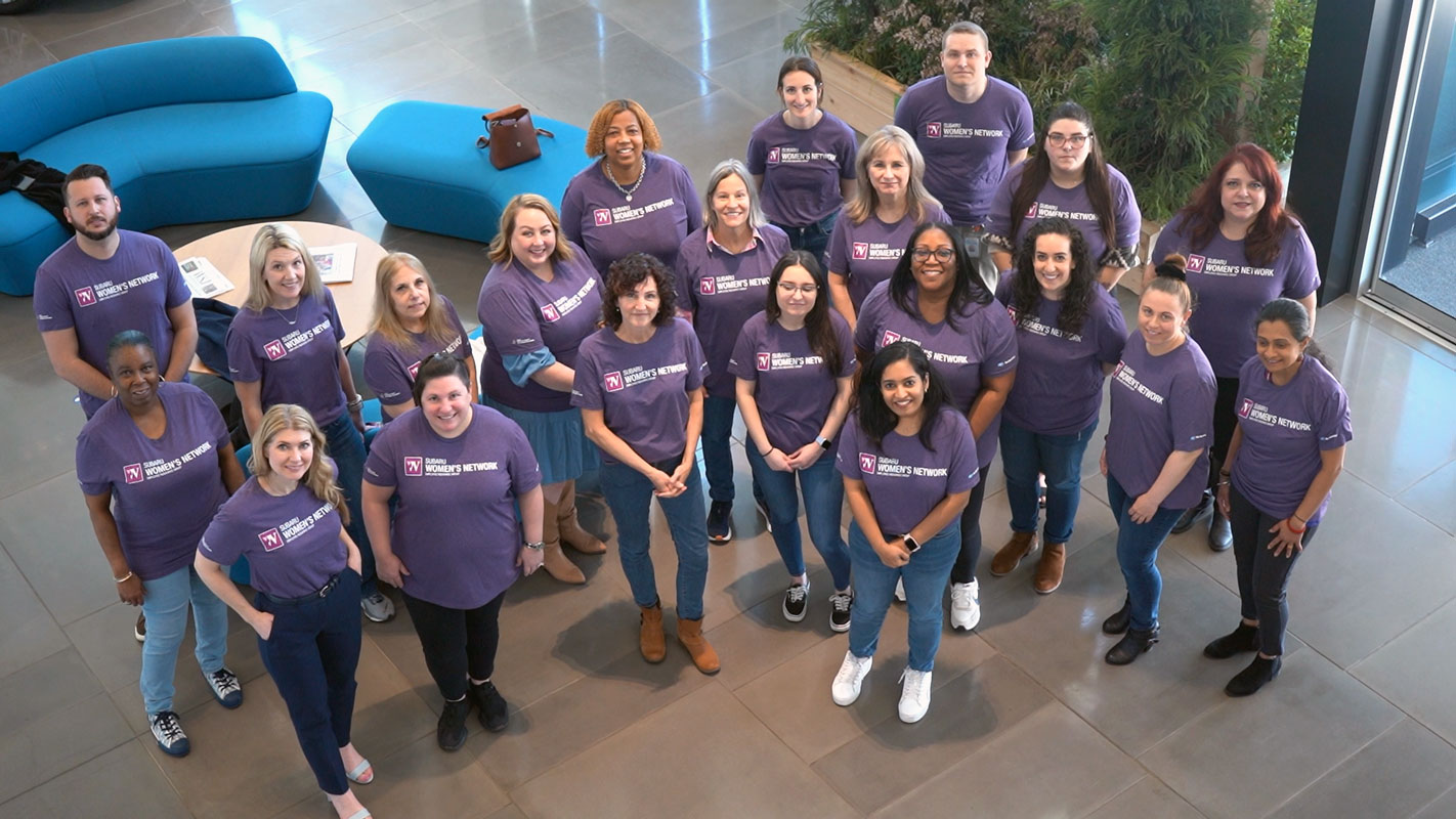 A diverse group of 20 people wearing matching purple 