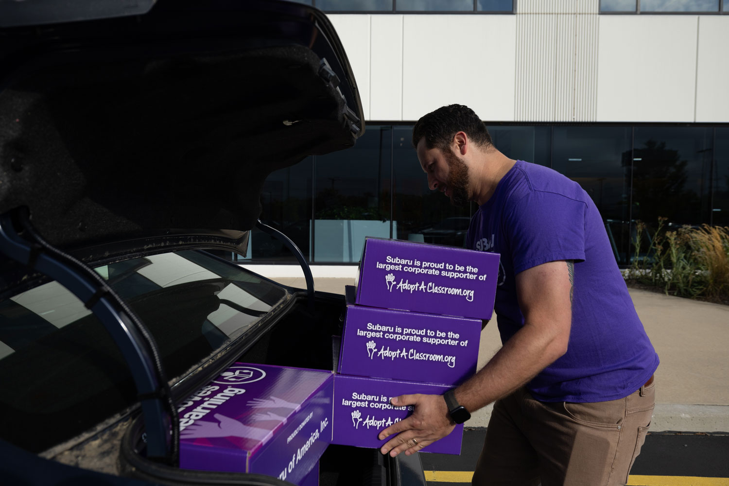 A man in a purple shirt loads purple boxes with
