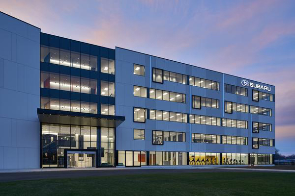 Modern, glass-fronted building at dusk, illuminated from within.