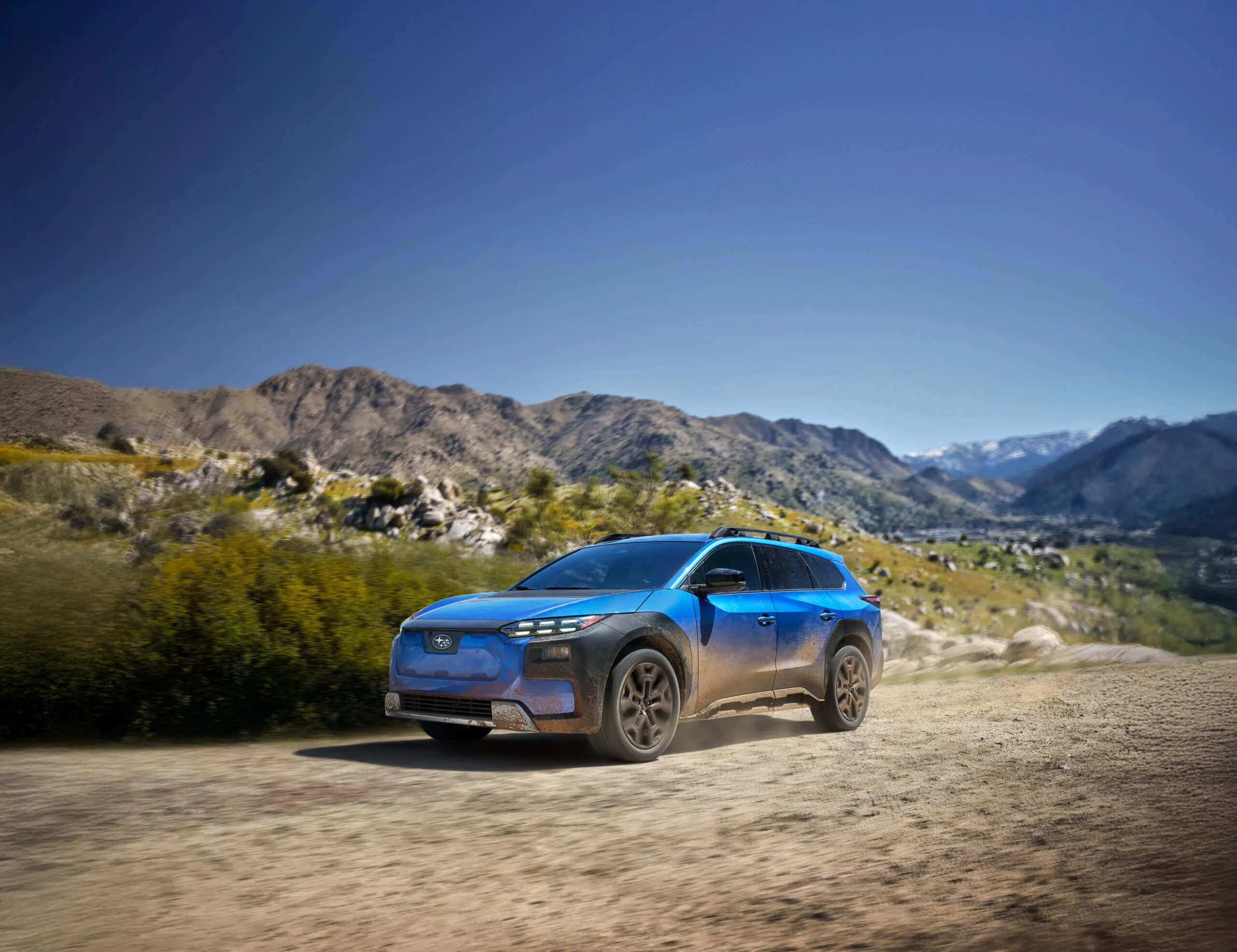 Blue Subaru Solterra driving on a mountain road.