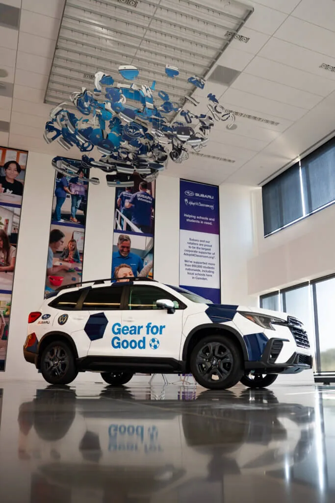 Subaru Ascent wrapped with Gear for Good branding on display beneath a sculpture made of donated soccer cleats