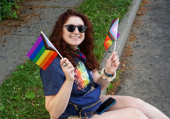 Woman holding 2 rainbow PFLAGs